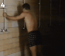 a shirtless man is standing in a shower with the number 4 on the bottom