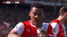 a soccer player covering his mouth with his hand during a game with a score of 5-0