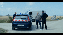 three men are standing in front of a gendarmerie vehicle