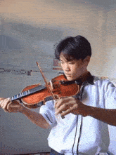 a young man in a white shirt is playing a violin in front of a white wall