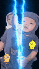 a baby with a yellow chick on his shirt is holding a blue lightning bolt