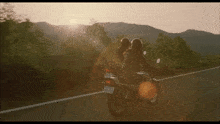 two people riding a motorcycle with a license plate that says 48-20