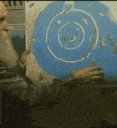 a man with a beard is holding a piece of blue paper with a white circle on it
