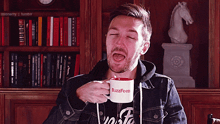 a man drinking from a buzzfeed mug with his mouth open