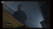 a man with a gun is standing on a set of stairs and says " oh you "