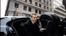 a man in a suit is getting out of a car