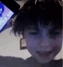 a young boy is smiling in front of a computer screen .