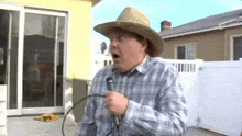 a man wearing a cowboy hat is holding a microphone and making a funny face .