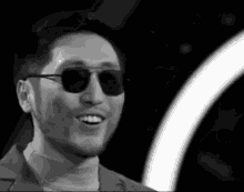 a black and white photo of a man wearing sunglasses and a suit .
