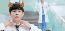 a man in a white coat and blue scrubs is standing next to a woman in a white coat