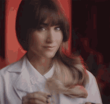 a woman in a lab coat is holding her hair and smiling