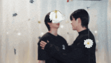 a couple of men are hugging each other in front of a wall with flowers on it .
