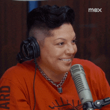 a woman wearing headphones and a red shirt with the word ard on the sleeve is smiling in front of a microphone