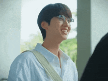 a young man wearing glasses and a white shirt is laughing .