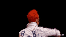 a man with red hair is wearing a white shirt with the letters rdb on the back .