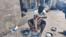 a man is sitting on the ground in front of a pot and cooking food .