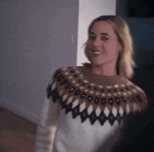 a woman wearing a sweater with a pattern on it smiles