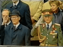a man in a military uniform is saluting in front of a crowd of people