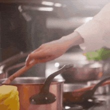 a person is stirring a pot of food with a wooden spoon