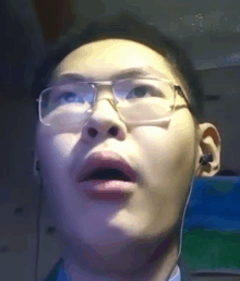 a close up of a man wearing glasses and ear buds with his mouth open .
