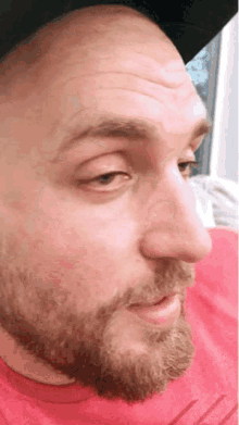 a man with a beard is wearing a red shirt and a hat