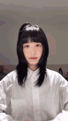 a girl with long black hair and a white shirt looks at the camera