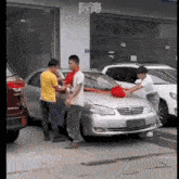 a group of people standing around a silver car with chinese writing on the side