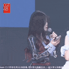 a girl holding a microphone in front of a sign that says cgt48
