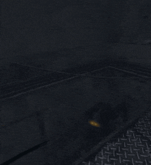 a dark room with a metal floor and a shadow of a person on the wall