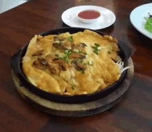 a plate of food on a wooden table with a bowl of dipping sauce