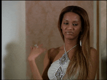 a woman wearing a white top with a necklace that has rhinestones on it