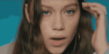 a close up of a woman 's face with her hand on her hair