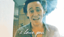 a man with curly hair is smiling and says `` i love you '' .