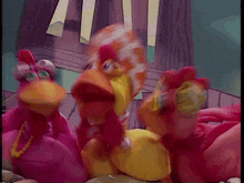 three stuffed chickens are standing next to each other in a cartoon scene .
