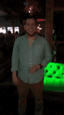 a man in a green plaid shirt is holding a glass