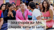 a group of people are sitting around a man in a pink suit and a woman in a pink dress