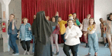 a group of people are dancing together in front of a red curtain .
