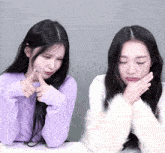 a woman in a purple sweater and a woman in a white sweater are making funny faces