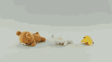 three stuffed animals including a brown bear a white cat and a yellow chick