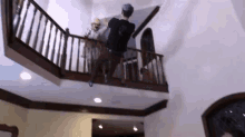 a man in a black shirt is standing on a balcony in a room .