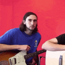 a man in a blue shirt is playing a guitar .