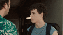 a man with curly hair is wearing a necklace