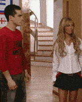 a man wearing a red shirt that says i have no idea stands next to a woman