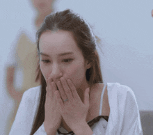 a woman with a ring on her finger covering her mouth with her hands