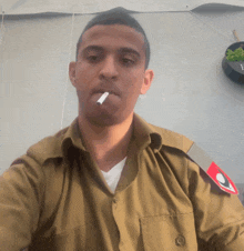 a man in a military uniform is smoking a cigarette in front of a wall with the letter f on it