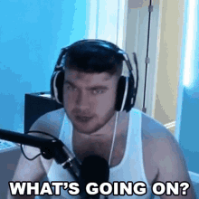 a man wearing headphones and a tank top is talking into a microphone .