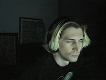 a man wearing headphones and a black shirt is looking at a computer screen .