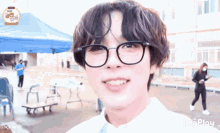 a young man wearing glasses looks at the camera