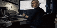 a woman sits at a desk in front of a computer