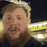 a man with a beard is standing in front of a sign that says ' efile house '